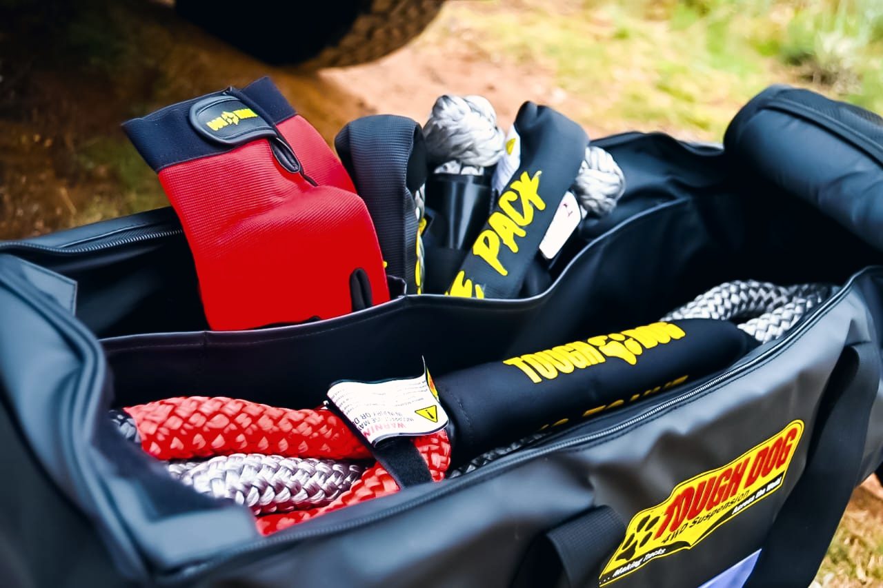 An open recovery bag holding a kinetic rope, soft shackles and a strap damper.
